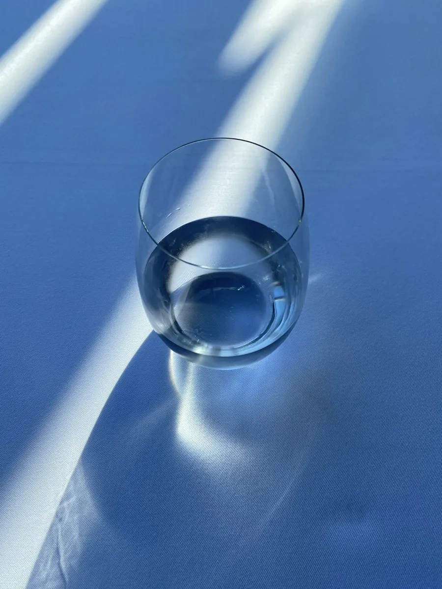 A glass of water casting a soft shadow across a blue tablecloth